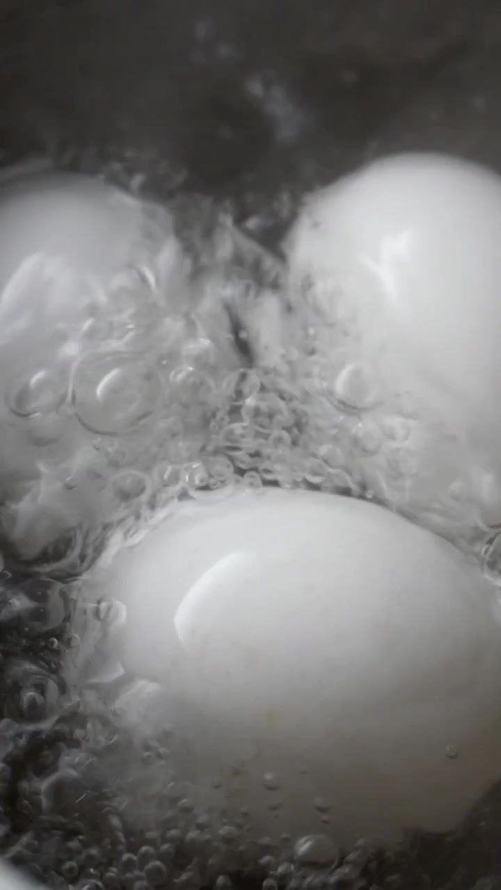 Primo piano di uova bianche che bollono in acqua calda