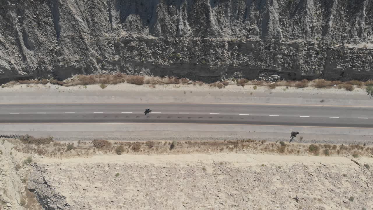 vista aérea de pájaro de la conducción de motocicletas a lo largo de la carretera costera de makran junto a espectaculares formaciones rocosas en el parque nacional hingol