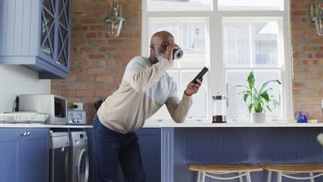 Afroamerikanischer-Mann,-älterer-Mann,-Der-Zu-Hause-Kaffee-Trinkt-Und-Sein-Smartphone-Benutzt