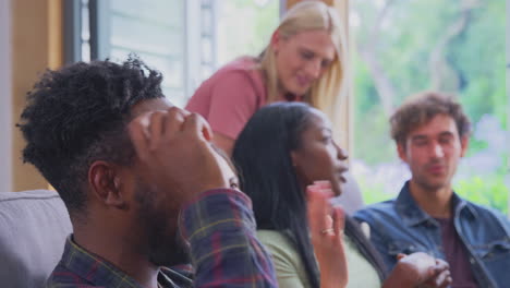 grupo multicultural de amigos sentados en sofás en casa disfrutando hablando juntos