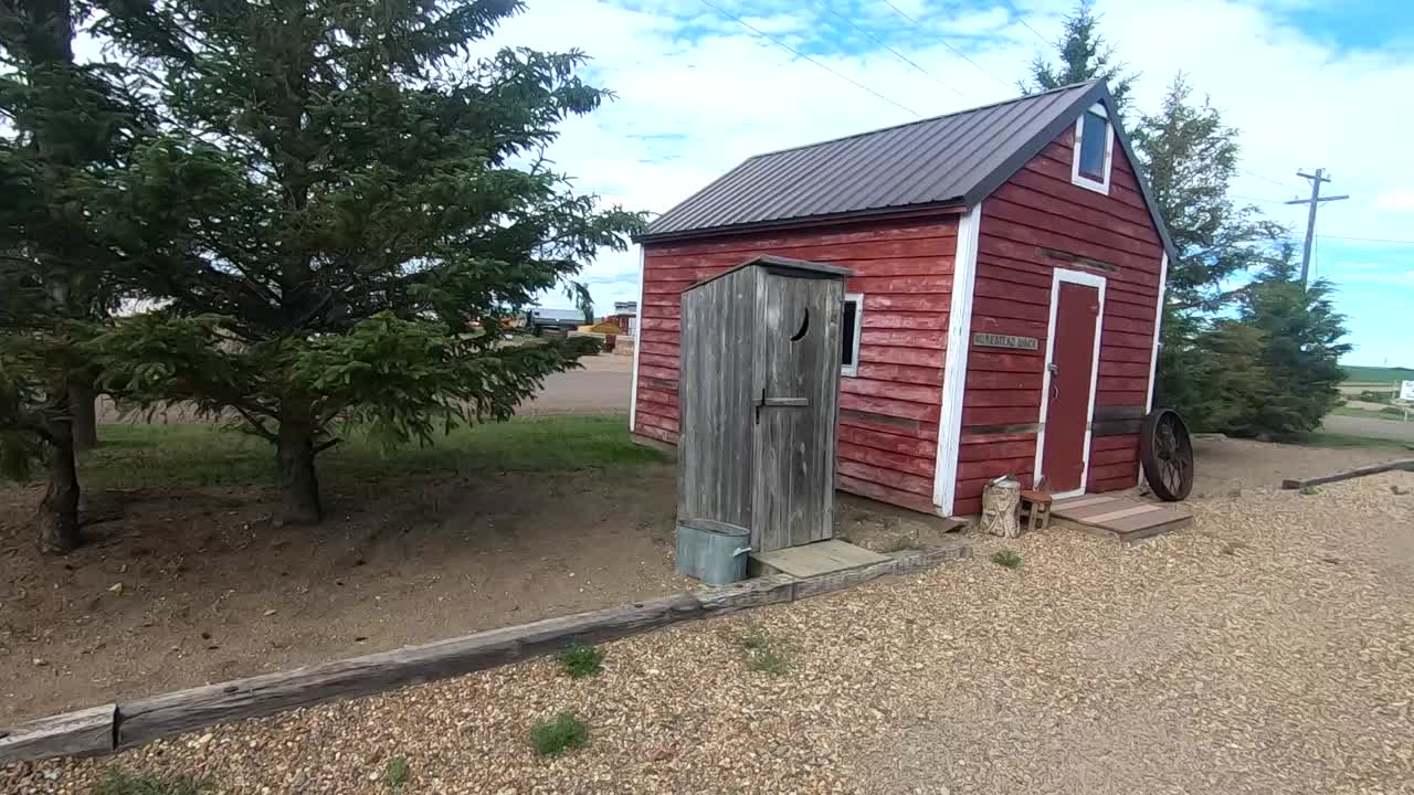 Old Wooden Outhouse outside next to a small red barn in Canada.