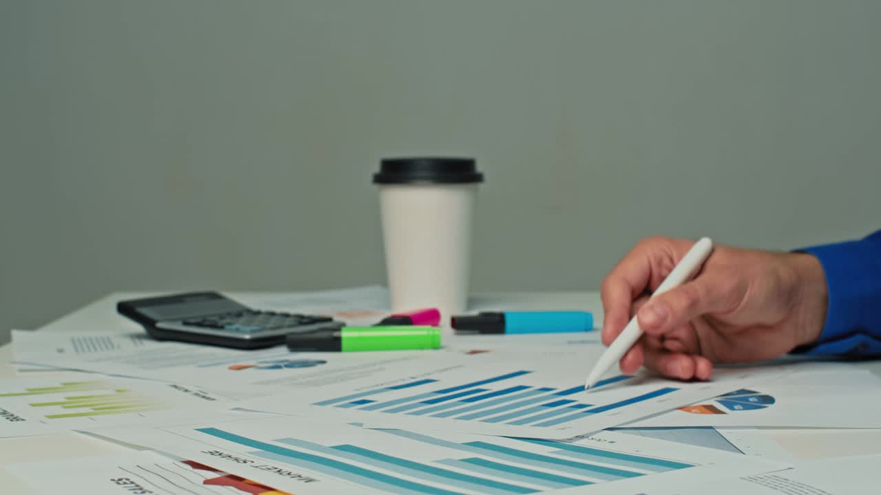 hombre de negocios sentado en su escritorio en la oficina, trabajando con documentos de estrategia de la compañía, corrigiendo gráficos, dibujando gráficos y estadísticas