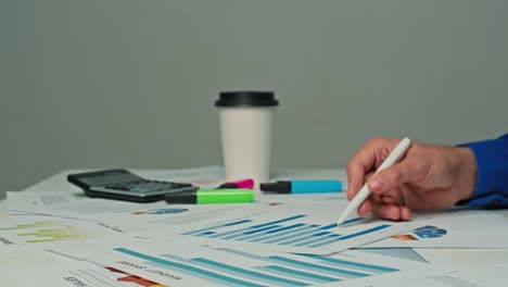 hombre de negocios sentado en su escritorio en la oficina, trabajando con documentos de estrategia de la compañía, corrigiendo gráficos, dibujando gráficos y estadísticas