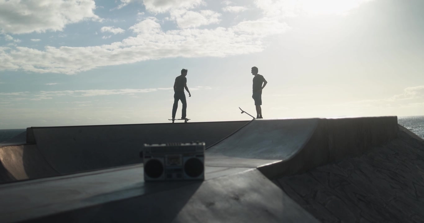 Silhouettes of Two Skaters with a Boombox at Sunset