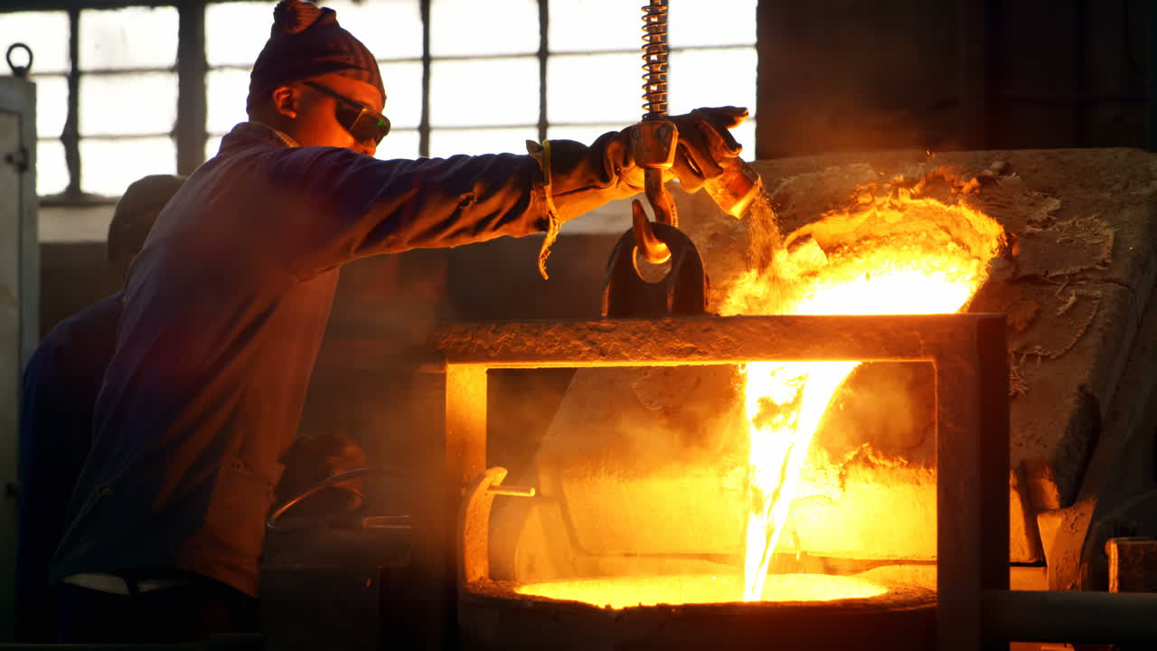 Male worker poring soil on molted metal  in workshop 4k