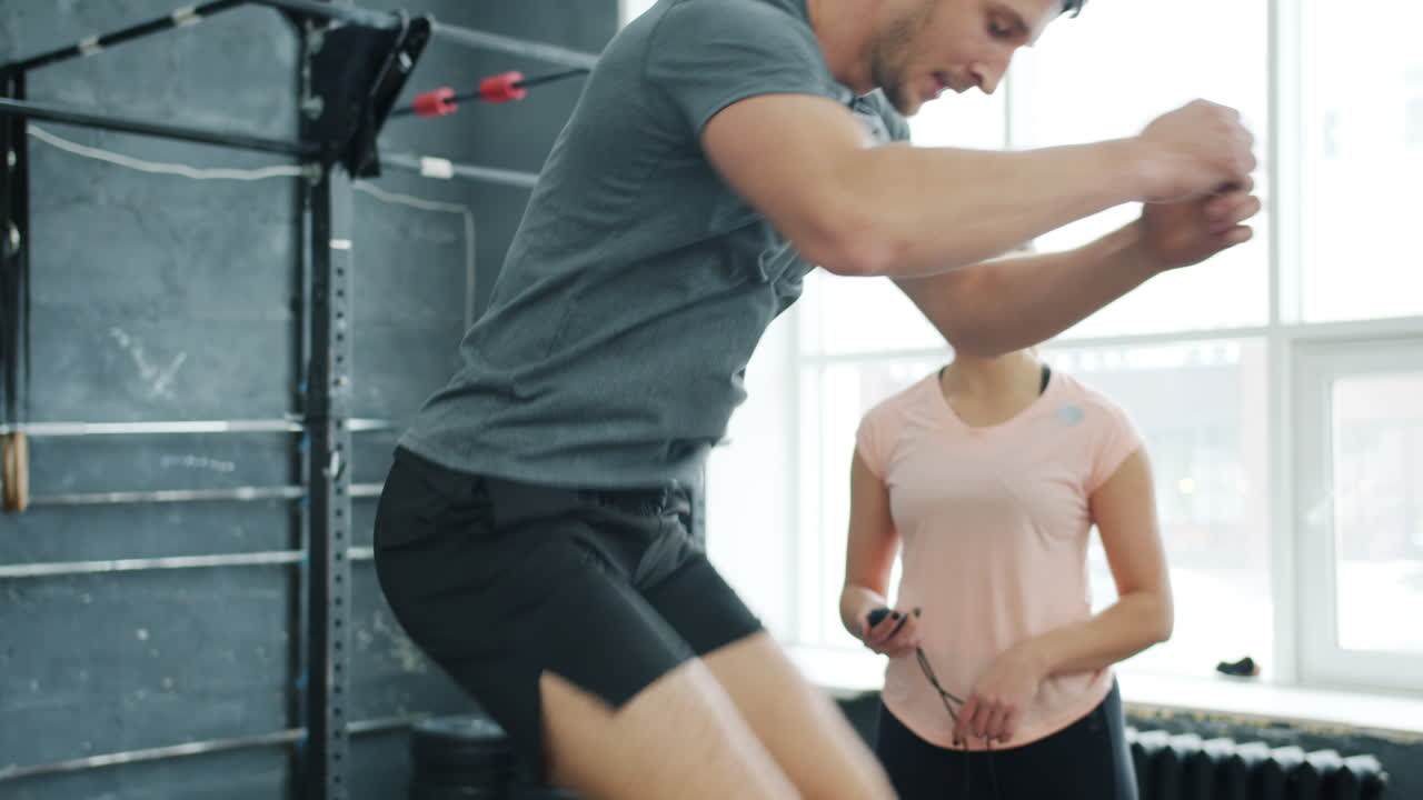 Man doing box jumps in the gym with a trainer