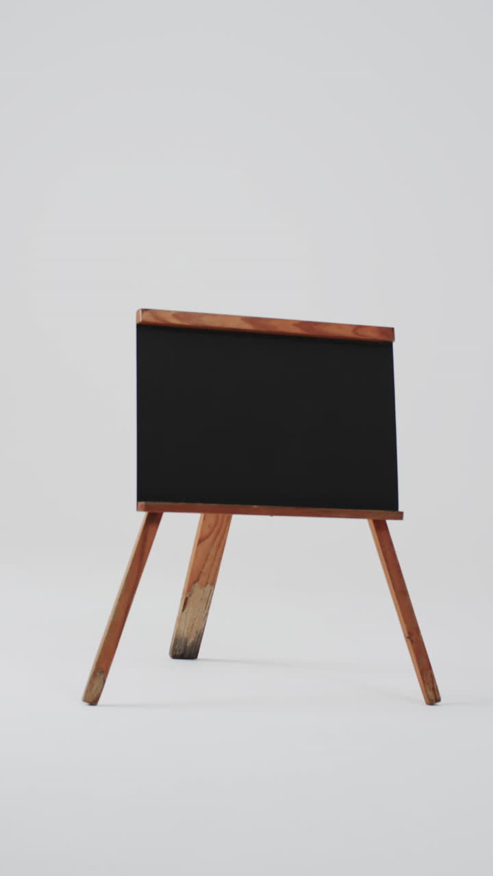 Video vertical de letrero de pizarra en soporte de madera con espacio para texto sobre fondo blanco.