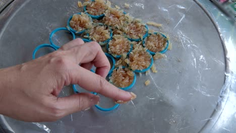 la mujer pone la mano de la mezcla de arroz con jugo de sandía en el molde para hacer pastel de arroz frito. la galleta de arroz es un bocadillo tradicional en tailandia.