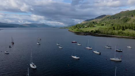 imágenes aéreas de drones de 4k alejándose de los veleros atracados en el lago loch cerca de las tierras altas escocesas de escocia