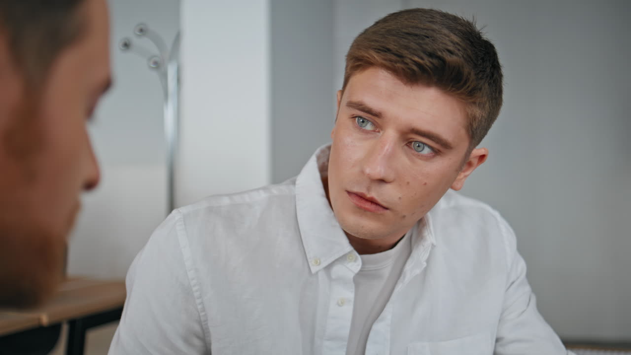 Serious man asking colleague at cabinet closeup. Young managers team talking