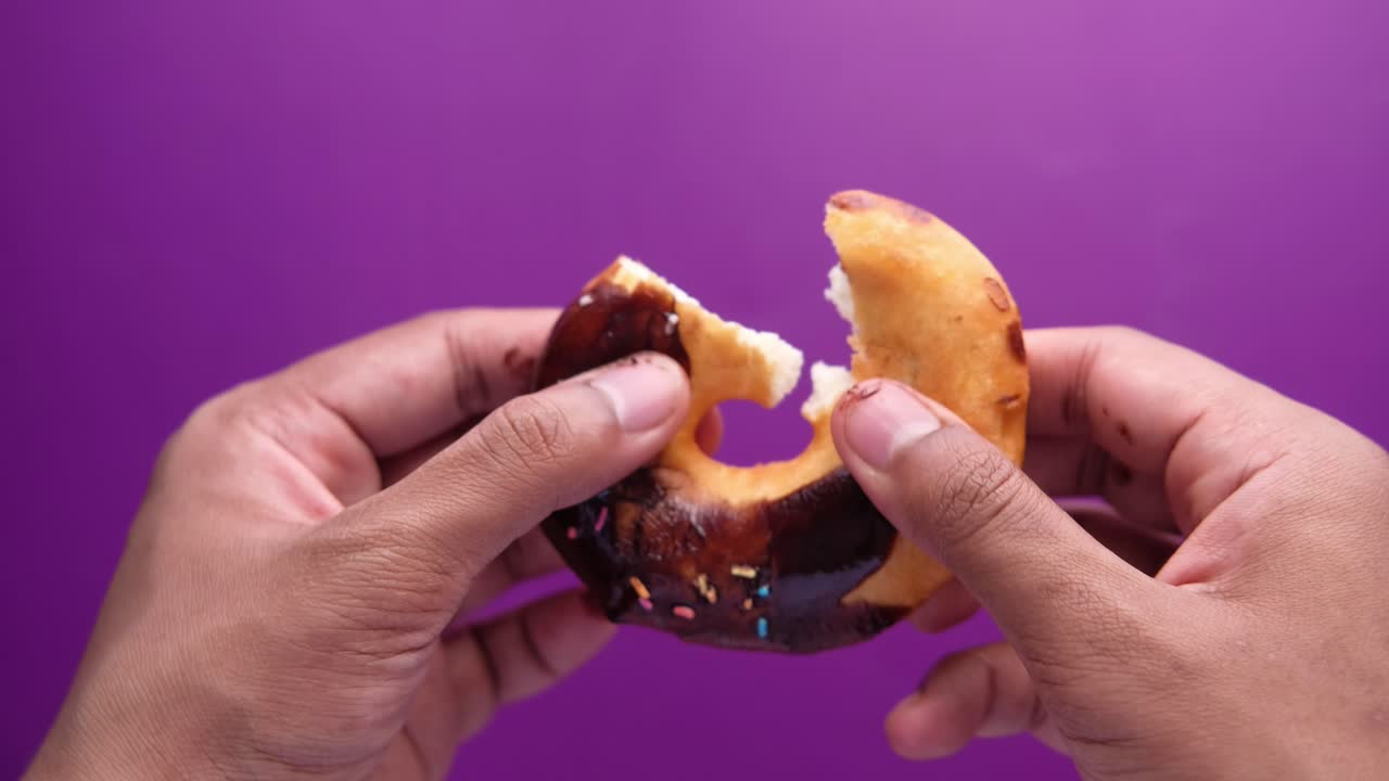 se está comiendo una rosquilla de chocolate.