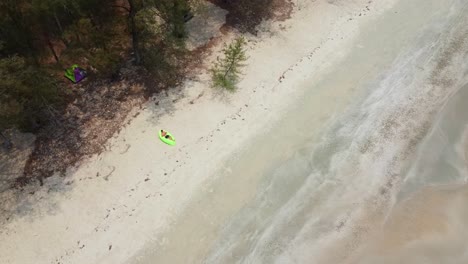 Hombre-Acostado-En-El-Sofá-De-Aire-Verde-En-La-Playa-De-Arena-Con-Carpa-Detrás