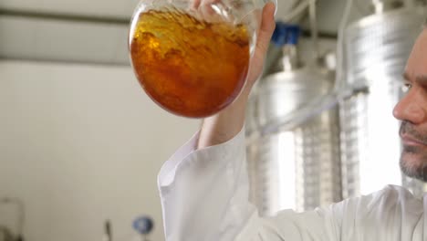 male worker examining liquor in flask 4k