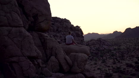 silueta de hombre sentado en el borde del acantilado, mirando el horizonte solo, sensación de paz y éxito