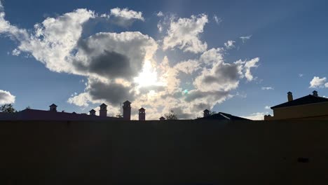 time lapse of rooftops with the sun behind clouds