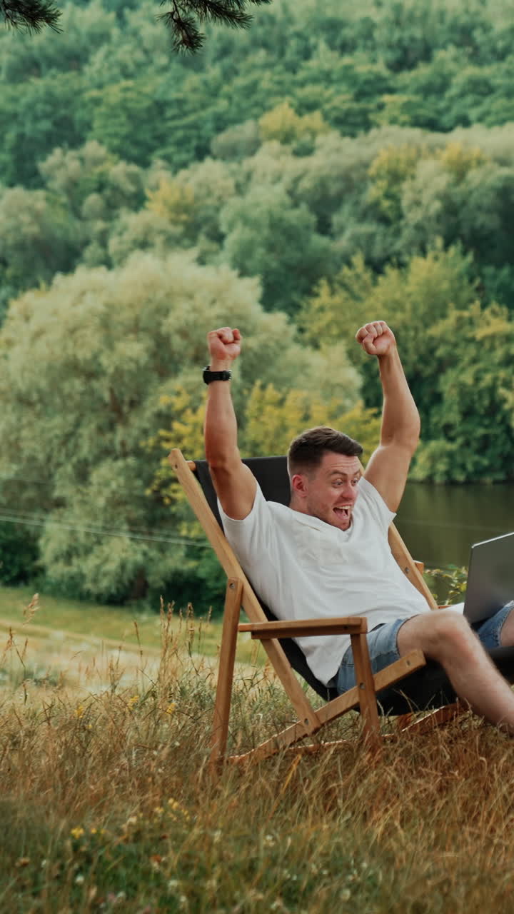 Man relaxing in a wooden chair in nature with laptop