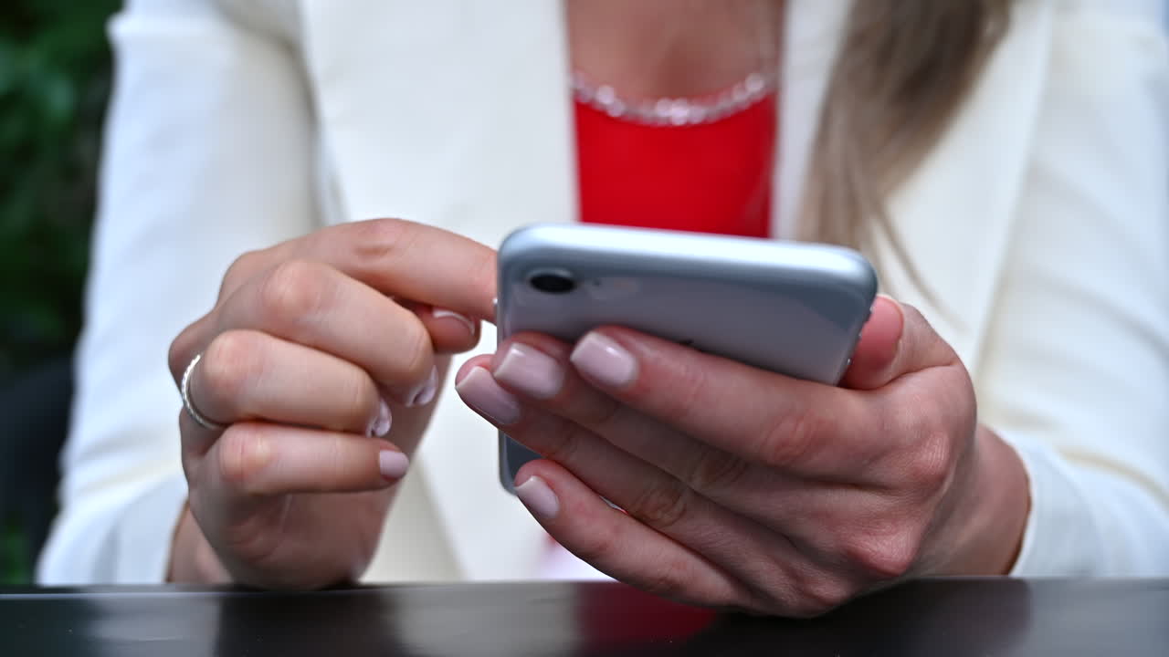 Donna bruna che scorre lo schermo del telefono a un tavolo su una terrazza