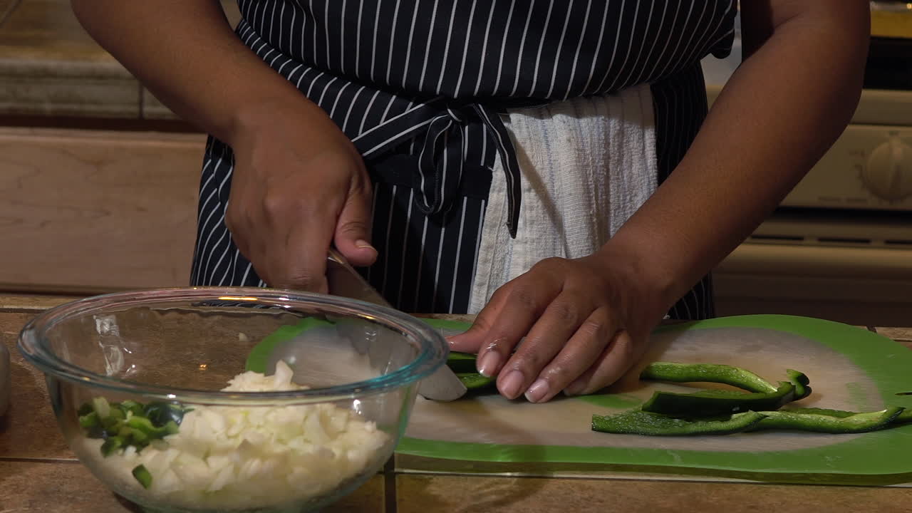 Slicing green bell peppers on plastic chopping board - Close up