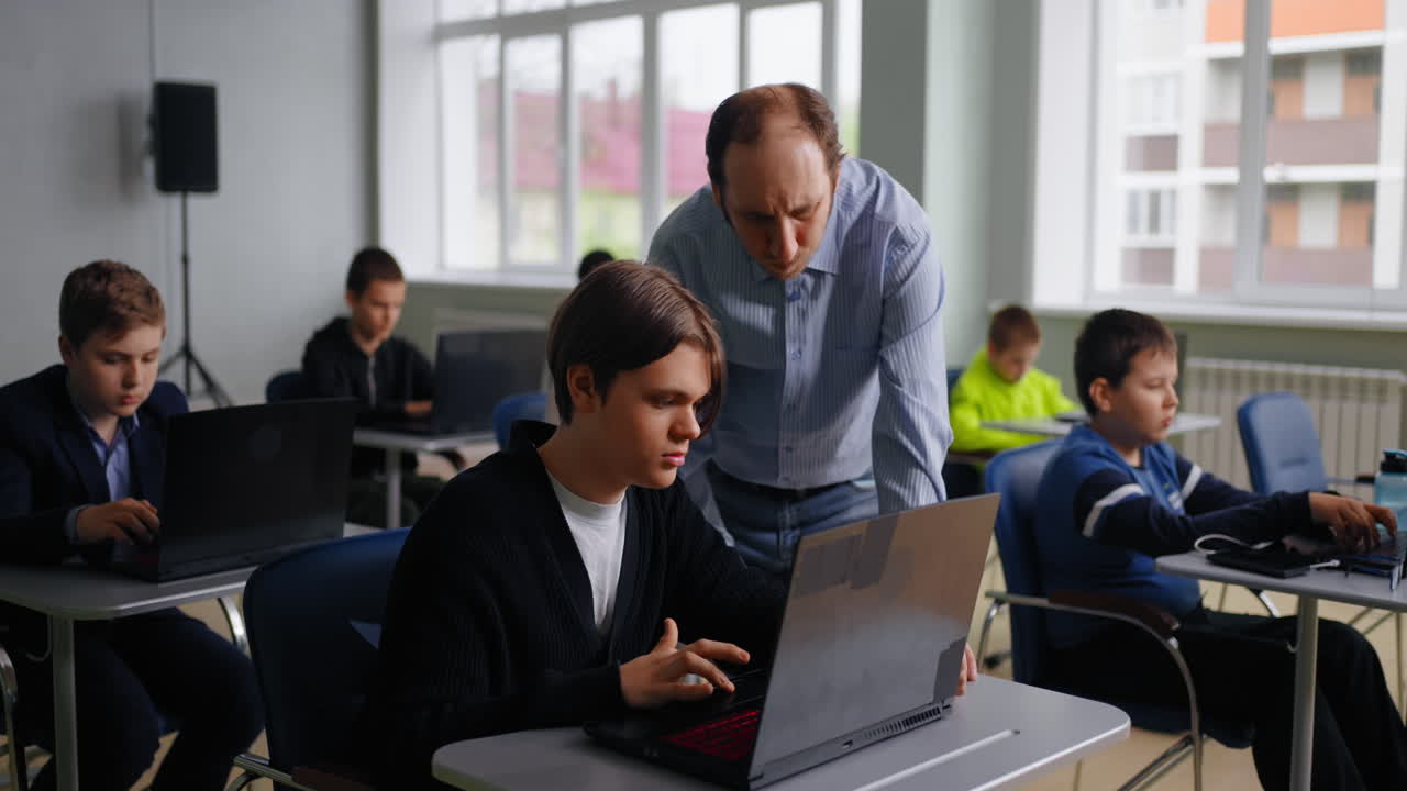 maestro ayudando al estudiante con una computadora portátil en el aula