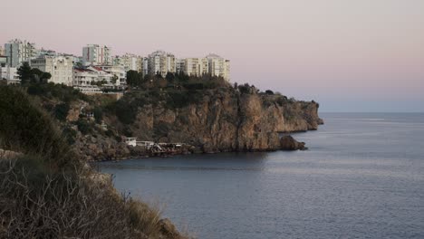 Volle-Aufnahme,-Malerischer-Blick-Auf-Das-Meer-Und-Die-Klippen-Von-Antalya,-Gebäude-Auf-Der-Rückseite-In-Der-Türkei