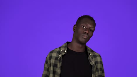 Happy-african-american-man-holding-hundred-dollar-banknotes-fan,-nodding-head-and-looking-at-camera-while-posing-against-blue-background-in-studio