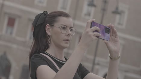 A-beautiful-girl-with-glasses-takes-a-photo-with-her-phone-while-on-vacation-in-Italy