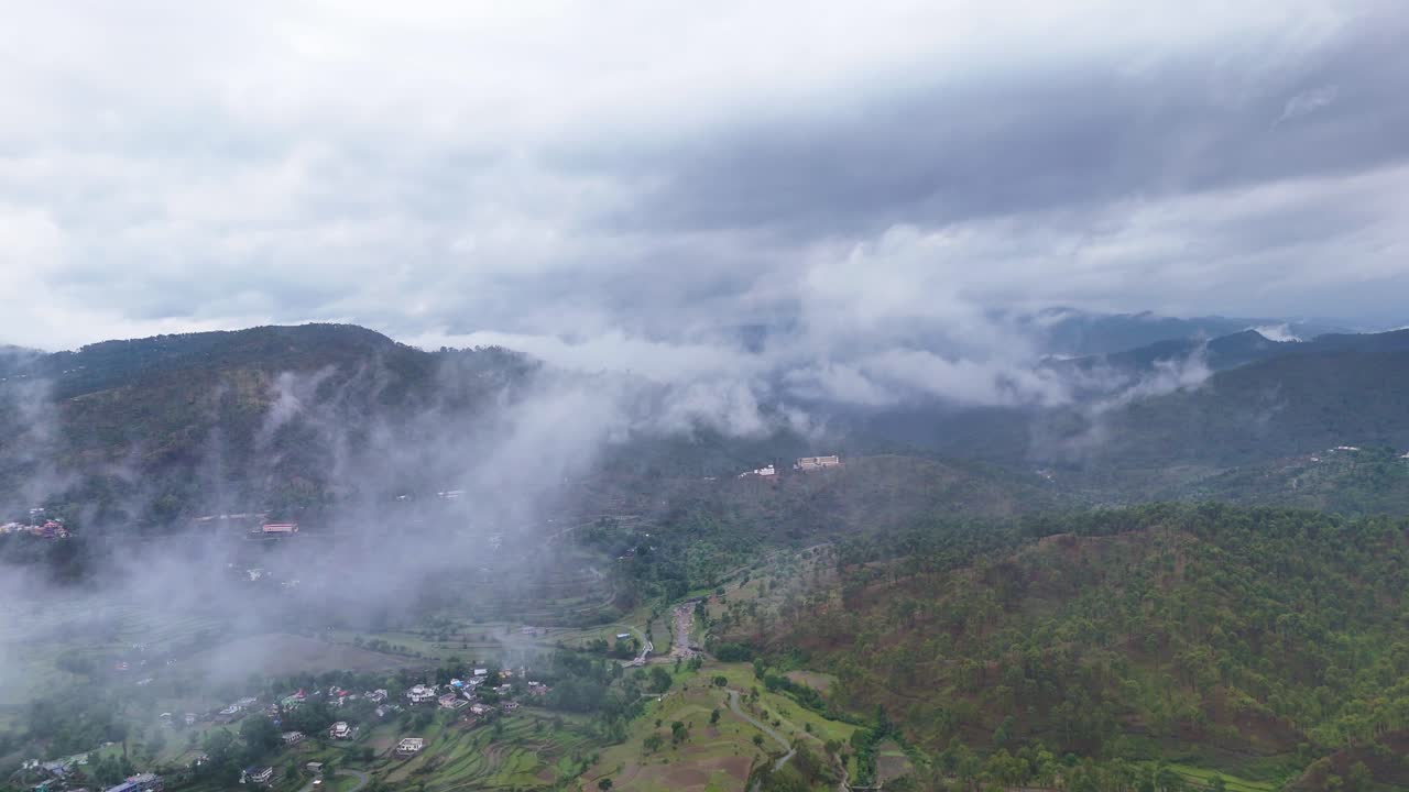 Aerial drone shot capturing the morning sun peeking over cloud-covered mountain peaks.