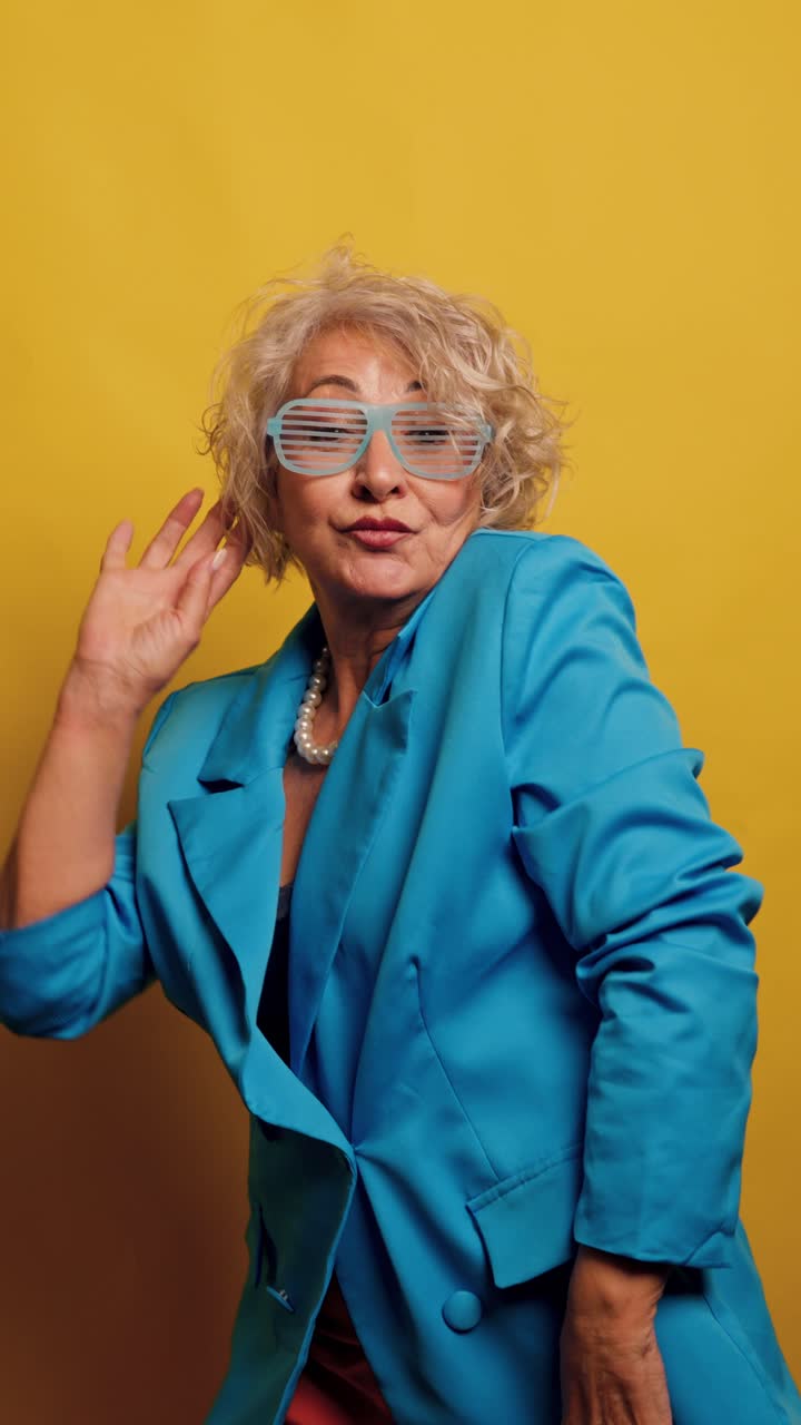 Signora anziana energica che balla e saluta con occhiali a persiana