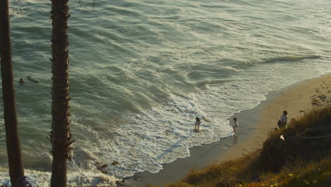 young children at a southern california beach during sunset joyfully play in the gentle ocean waves breaking the shoreline