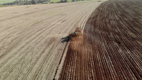 aerial view shot of a farmer in tractor seeding, sowing agricultural crops at field