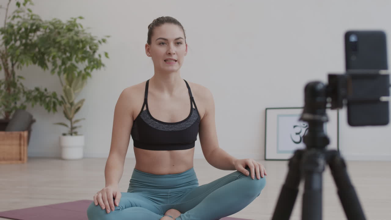 mujer caucásica filmando su práctica de yoga en video
