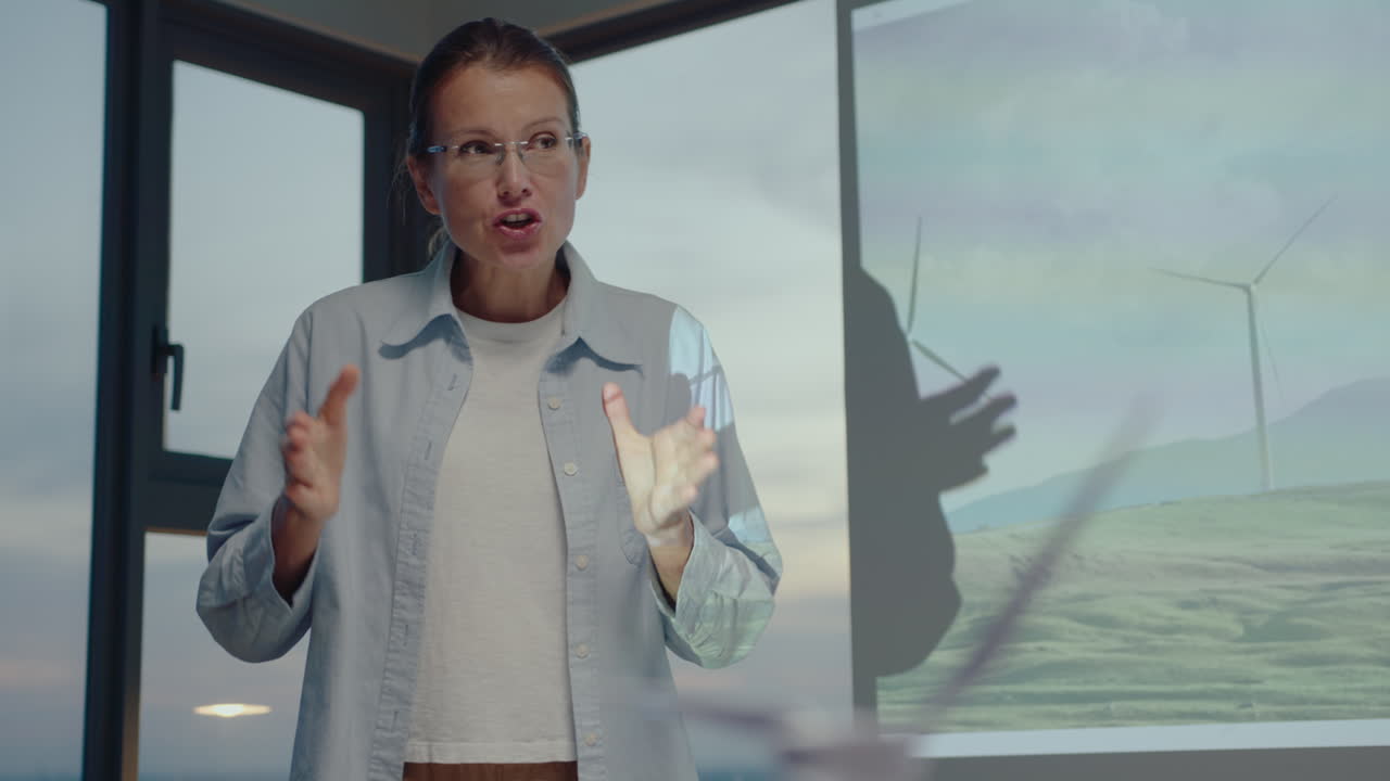 líder de equipo femenina explicando la presentación sobre el parque eólico en la pantalla de proyección a los colegas durante una reunión de negocios en una compañía de energía renovable en la oficina.