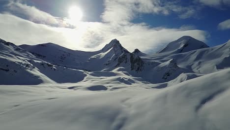 Drone-slowly-rising-vertically-to-reveal-mountain-range-in-distance-in-winter