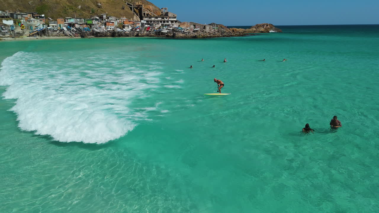 Aerial view of a man paddling and surfing a wave on a SUP board in sunny Brazil
