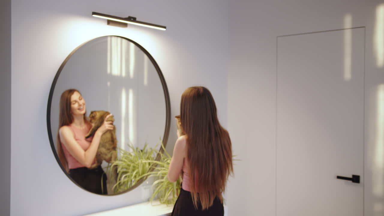 거울 앞에서 고양이와 놀고 있는 여자