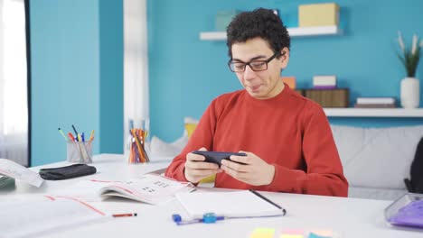 El-Niño-Travieso-Juega-Con-El-Teléfono-En-Lugar-De-Estudiar,-Y-Luego-Se-Despierta-Y-Estudia.