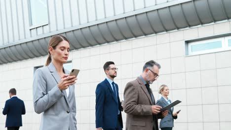 joven empresaria caucásica caminando por la calle y usando un teléfono inteligente