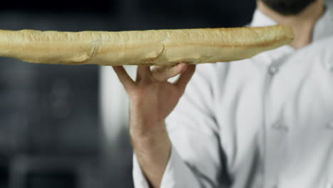 chef having fun with french bread at kitchen. closeup man hands play with bread