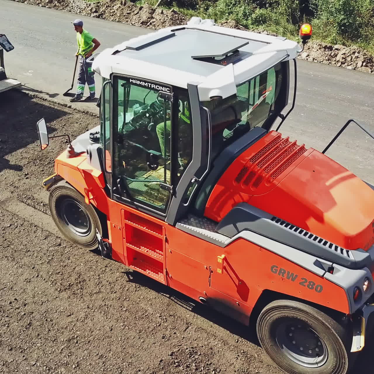 Large road-roller paving a road. Road construction. Aerial view.