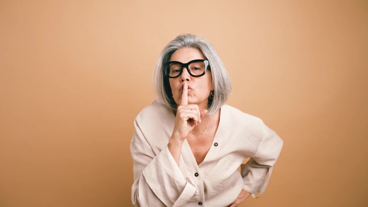 Mujer madura con canas haciendo un gesto de silencio