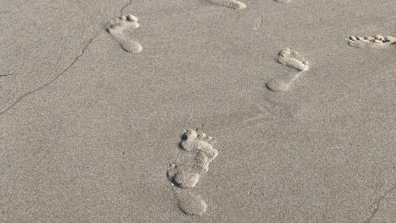 Cape Town'da bir plajın kıyısındaki kumların üzerinde ayak izleri