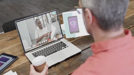 Caucasian-businessman-on-laptop-video-call-with-african-american-female-colleague-on-screen