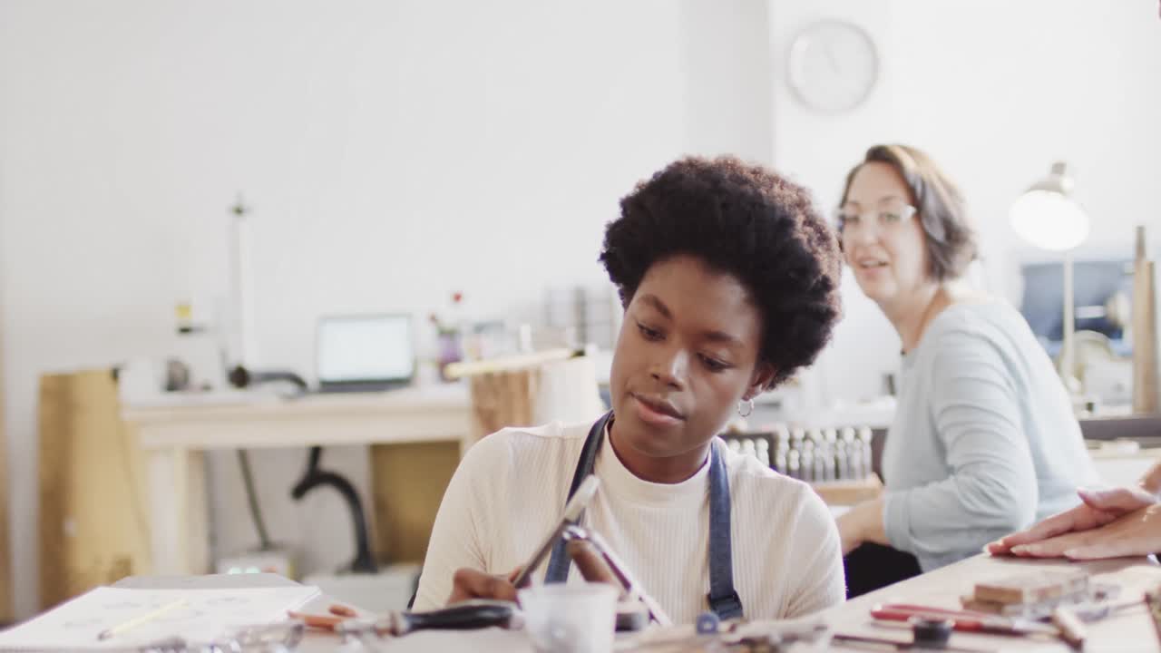 Busy diverse female workers shaping ring with handcraft tools in studio in slow motion