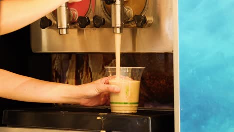 person filling cup with slushy drink