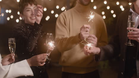 gruppe von vier multiethnischen freunden mit champagnergläsern, die sich auf der silvesterparty mit wunderkerzen vergnügen 1