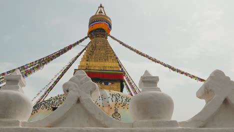 panning clip looking upwards at elaborate golden temple in kathmandu, nepal, with white carved decorations in foreground