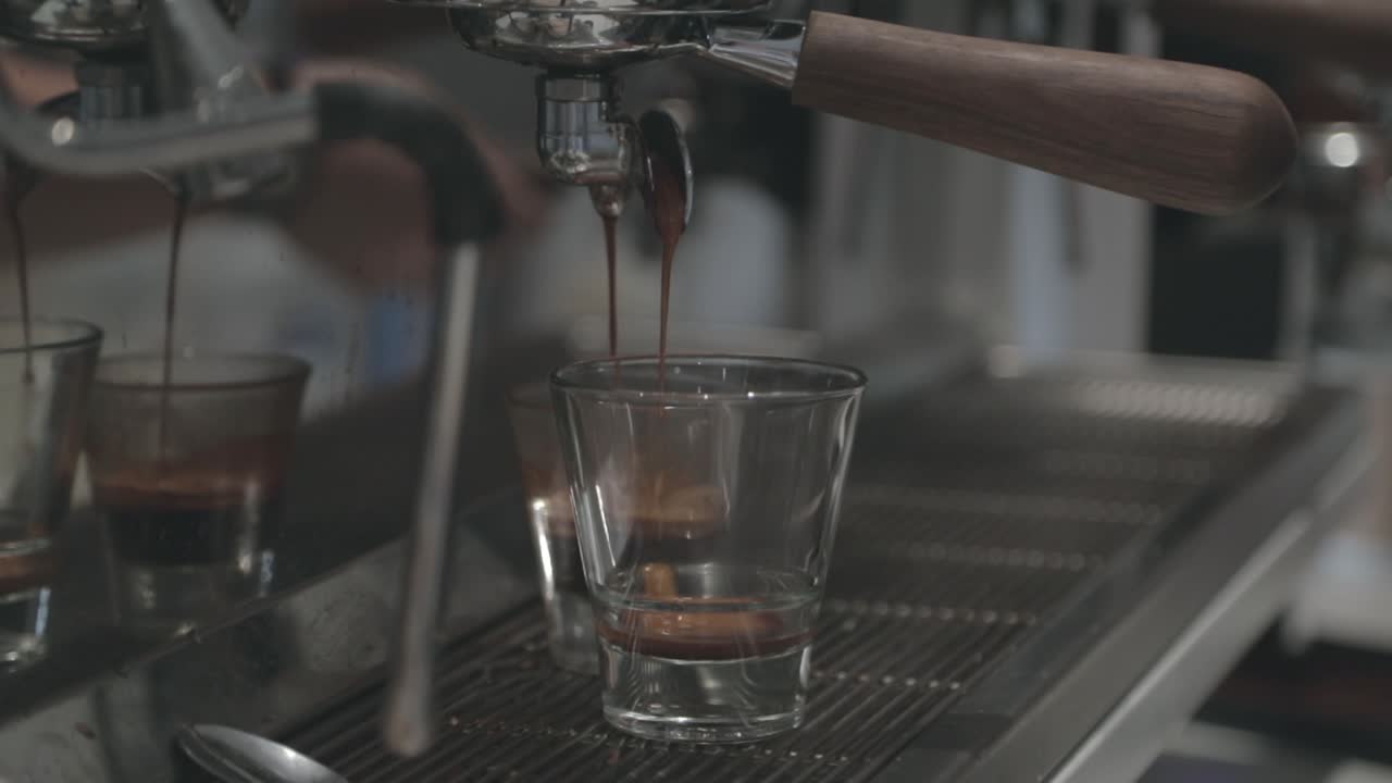 Una macchina da caffè espresso versa il caffè in due tazzine al rallentatore.