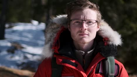 hombre caucásico caminando hacia la cámara a través de un bosque nevado