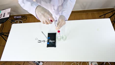 scientist conducts a chemical reaction using lead nitrate and potassium iodide in a lab setting with controlled lighting