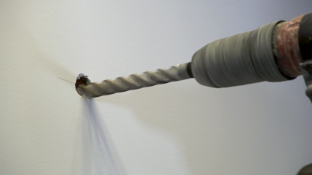 Close-up shot of a hole being drilled on the marked spot on a wall